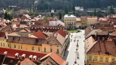 BRASOV, ROMANIA - Nisan 2022: Romanya 'nın Barsov kentinin insansız hava aracı görüntüsü. Yürüyen insanlarla dolu bir yaya sokağı, etrafında eski binalar.