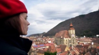 Romanya 'nın eski Brasov merkezine bakan bir kadın. Siyah Kilise, eski yerleşim yerleri, tepeler, bulutlar.