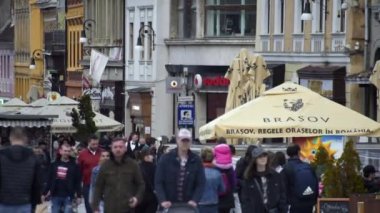 BRASOV, ROMANIA - Nisan 2022: Eski şehir merkezi manzarası. Bir sürü yürüyen insan, restoran ve eski binalarla dolu bir yaya sokağı.