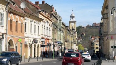 BRASOV, ROMANIA - Nisan 2022: Eski şehir merkezi manzarası. Eski binalar, yürüyen insanlar, arabalar.