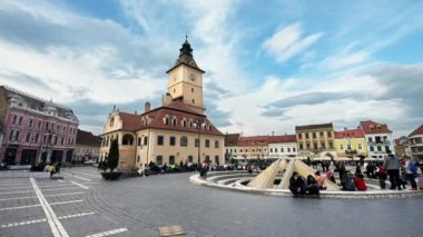 BRASOV, ROMANIA - Nisan 2022: Eski şehir merkezindeki Konsey Meydanı manzarası. Klasik binalar, bir sürü dinlenen insan.