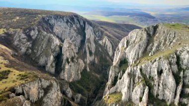 Romanya 'daki kayalık bir kanyonun insansız hava aracı görüntüsü. İnce bitki örtüsü olan kayalık kayalıklar. Uzaktaki alanlar