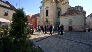 CLUJ, ROMANIA - Nisan 2022: Şehir merkezinin sokak manzarası. İnsanlarla, kiliseyle ve eski binalarla dolu.