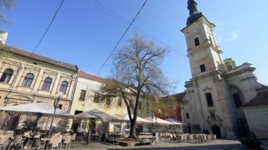 CLUJ, ROMANIA - Nisan 2022: Cluj şehir merkezinin sokak manzarası, Romanya. Kilisesi, insanları, restoranları ve eski binaları olan bir meydan.
