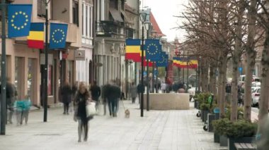 CLUJ, ROMANIA - Nisan 2022: Şehir merkezinin sokak manzarası, zaman ayarlı. Yürüyen bir sürü insan, bayraklar, eski binalarla dolu bir yaya sokağı.