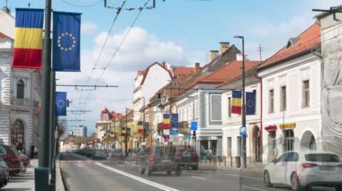 CLUJ, ROMANIA - Nisan 2022: Şehir merkezinin zaman gösterimi. Yürüyen insanlar, arabalar, klasik tarzda yapılmış eski binalar.