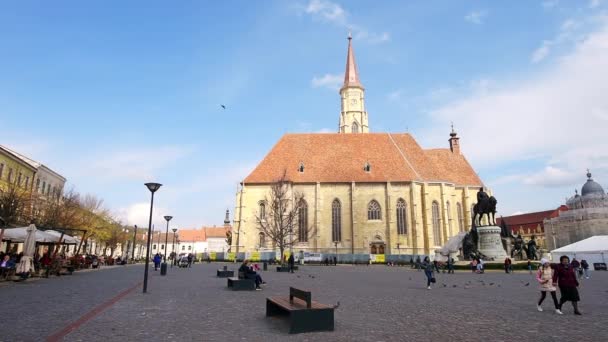 Cluj Romania エイプリル 2022 市街地の街並み 聖ミカエル教会とその前にマティアス コルヴィヌスの像を持つ中央広場 人々を歩く — ストック動画