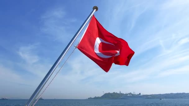 イスタンブールの旗竿にトルコ国旗を振っている 遠くの土地と船 — ストック動画