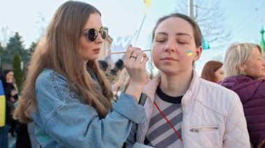 CHISINAU, MOLDOVA - Nisan 2022: Rusya 'nın Ukrayna' nın merkezdeki işgaline karşı protestolar. Yanağında Ukrayna bayrağı olan bir kadın resmedilmiş.