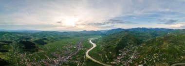 Romanya 'nın Maramures kentindeki doğanın insansız hava aracı görüntüsü. Karpat Dağları, çevresi yemyeşil ormanlarla kaplı bir vadide yer alan bir kasaba, nehir.