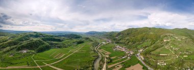 Romanya 'nın Maramures kentindeki doğanın insansız hava aracı görüntüsü. Karpat Dağları, çevresi yemyeşil ormanlarla kaplı bir vadide yer alan bir kasaba, nehir.