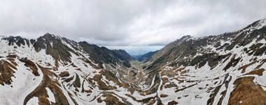 Romanya 'daki hava aracı doğaya panoramik açıdan bakıyor. Karpat dağlarında arabalı transfagarasan rotası, vadide karla kaplı dağlar.