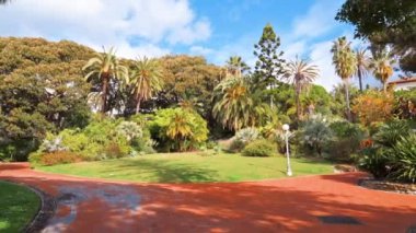 İtalya, Sanremo 'da bir park manzarası. Yürüyen bir kadın ve bir sürü yeşillik.