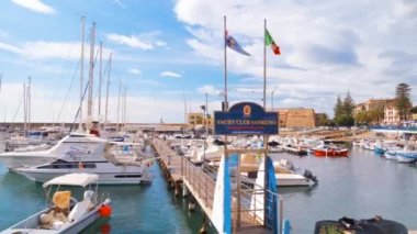 SANREMO, İtalya - MAYIS 2022: Birden fazla demirli yat ve tekneli Akdeniz limanı, arka planda klasik binalar