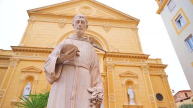 İtalya, Sanremo 'da arka planda bir rahip heykeli ve bir kilise olan meydan.