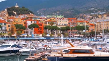 Akdeniz limanında birden fazla demirli yat ve tekne var. Sanremo, İtalya 'da arka planda klasik binalar.
