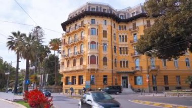 SANREMO, İTALYA - MAYIS 2022: Klasik tarzda yapılmış, önünde arabalar ve yeşillik olan bir ev.