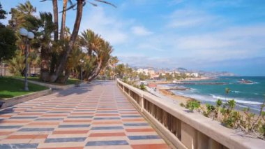 SANREMO, İtalya - Mayıs 2022 Akdeniz kıyısı. Toprak döşeme sokağında bir sürü insan ve yeşillik var.