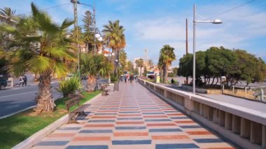 SANREMO, İTALYA - MAYIS 2022: Yürüyen insanlar ve hareket halindeki arabalarla dolu bir sokak. Bir sürü yeşillik, Akdeniz kıyısı.