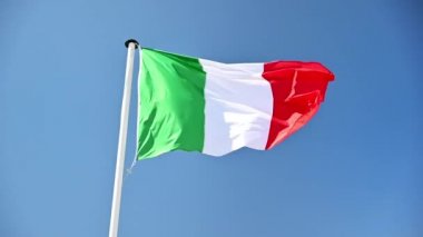 İtalyan bayrağı bayrak direğinde rüzgarda dalgalanıyor. Arka planda mavi gökyüzü. Yavaş çekim