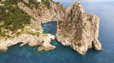 İtalya, Capri 'deki Tyrhenian deniz kıyılarının insansız hava aracı görüntüsü. Kayalık kayalıklar, mavi su, yüzen kayıklar, yeşillik