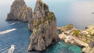 İtalya, Capri 'deki Tyrhenian deniz kıyılarının insansız hava aracı görüntüsü. Kayalık kayalıklar, mavi su, yüzen kayıklar, yeşillik