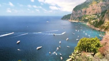 İtalya, Capri 'nin Tyrhenian deniz kıyıları. Kayalık kayalıklar, mavi su, birden fazla yüzen tekne, yeşillik