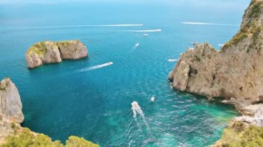 İtalya, Capri 'nin Tyrhenian deniz kıyıları. Kayalık kayalıklar, mavi su, birden fazla yüzen tekne, yeşillik