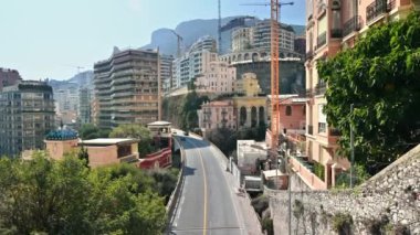 Monako - Mayıs 2022: Monako şehri manzarası. Hareket eden arabalarla köprü, birden fazla konut binası olan tepeler, yeşillik