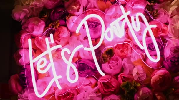 Permite Fiesta Brillante Signo Neón Rosa Con Flores Fondo — Vídeos de Stock