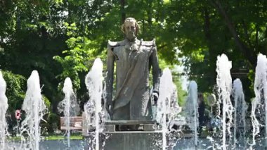 BUCHAREST, ROMANIA - Mayıs 2022: Çeşme, yeşillik ve dinlenen insanların olduğu parkta bir heykel