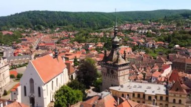 Romanya 'nın Sighisoara Tarih Merkezi' nin insansız hava aracı görüntüsü. Eski binalar, dar sokaklar, Sighisoara Saat Kulesi, çevresindeki yeşil tepeler.