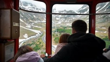 İçeriden dağın tepesine giden ve içinde yolcular olan bir teleferik görüntüsü. Karpatya dağlarında transfagarasan rotası