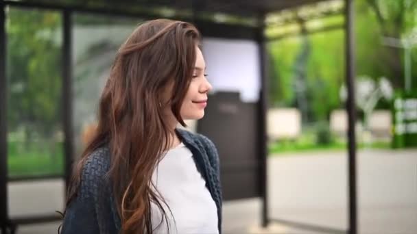 スマートフォンを持つ女性トロリーバスの駅で歩くと 背景に他の人 スローモーション — ストック動画