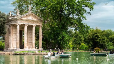 ROMA, İTALYA - 2022 Villa Borghese Bahçeleri içinde yüzen insanlar, yeşillik ve antik Roma binası