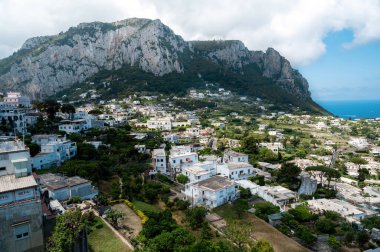 Capri, İtalya şehir manzarası. Yerleşim alanları, Tyrhenian deniz kıyıları, yeşillik ve kayalık dağlar. Bir tepeden bak