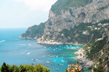 İtalya, Capri 'nin Tyrhenian deniz kıyıları. Kayalık kayalıklar, mavi su, birden fazla yüzen tekne, yeşillik
