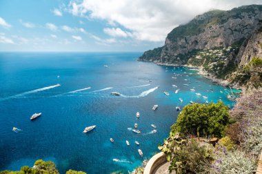 İtalya, Capri 'nin Tyrhenian deniz kıyıları. Kayalık kayalıklar, mavi su, birden fazla yüzen tekne, yeşillik
