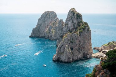 İtalya, Capri 'nin Tyrhenian deniz kıyıları. Kayalık kayalıklar, mavi su, birden fazla yüzen tekne, yeşillik