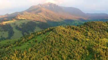 Aerial drone view of Ceahlau national park in the Carpathians in Romania at sunset. Hills covered with lush forest