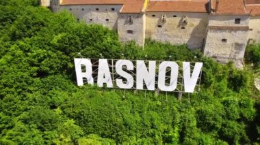 Romanya 'daki Rasnov Kalesi' nin insansız hava aracı görüntüsü. Tepenin tepesinde Rasnov yazıtı olan ortaçağ kalesi, Karpatlar