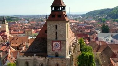 Romanya 'nın eski Brasov merkezindeki Kara Kilise' nin insansız hava aracı görüntüsü. Çevresindeki eski binalar, yeşillikli tepeler.