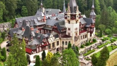 Romanya 'daki Peles Kalesi' nin insansız hava aracı görüntüsü. Karpatlar 'da bahçeleri ve turistleri olan bir kale. Etrafında bereketli ormanlar var.