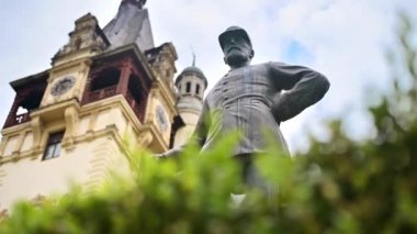 Romanya 'daki Peles Kalesi' nde Kral Carol heykeli. Arka planda Castle