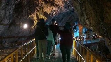 BUCEGI, ROMANIA - Haziran 2022: Bucegi Dağlarındaki Ialomitei Mağarası. Yürüyen turistler, köprüler, aydınlanma
