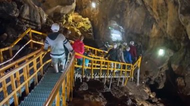 BUCEGI, ROMANIA - Haziran 2022: Bucegi Dağlarındaki Ialomitei Mağarası. Yürüyen turistler, merdivenler, aydınlatma