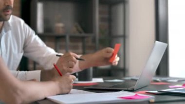 Ofiste çalışan ve konuşan bir kadın ve bir erkek. Bilgi içeren araç gereçler ve belgeler