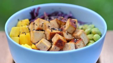 Cook filling vegan poke with seeds. Vegetables and tofu. Slow motion