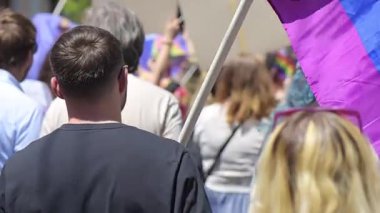 Lots of people at the gay pride parade in the center of Chisinau, Moldova. Multiple rainbow flags and posters. Slow motion
