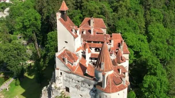 从空中俯瞰罗马尼亚的布兰城堡 喀尔巴阡山脉中的中世纪城堡 里面有游客 周围绿树成荫 — 图库视频影像